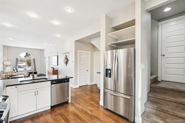 kitchen with sink, stainless steel appliances, white cabinetry, and dark wood-type flooring