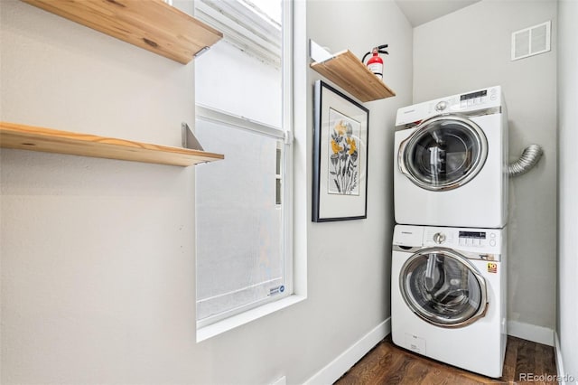 laundry area with stacked washer / dryer and dark wood-type flooring