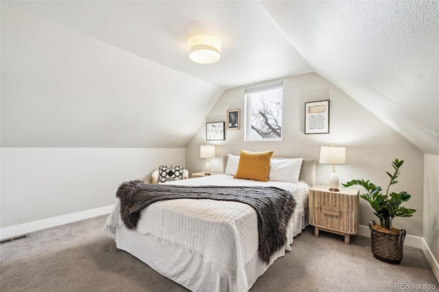 bedroom with carpet, a textured ceiling, and vaulted ceiling