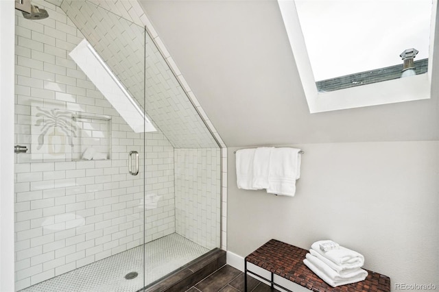 bathroom with an enclosed shower and vaulted ceiling with skylight