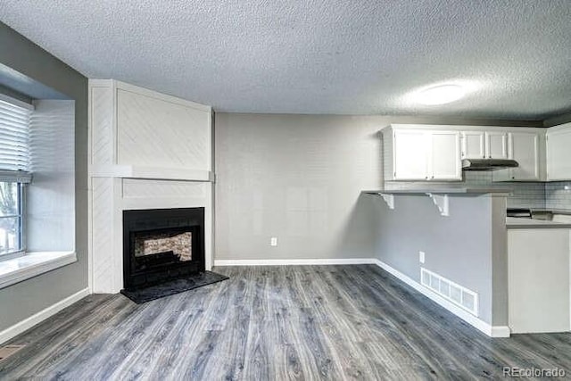 18131 E Arizona Ave Unit F, Aurora, CO 80017 - unfurnished living room featuring dark wood finished floors, a textured ceiling, and a large fireplace