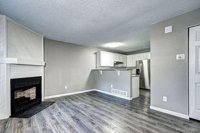 18131 E Arizona Ave Unit F, Aurora, CO 80017 - unfurnished living room featuring a textured ceiling, dark wood-type flooring, and a fireplace
