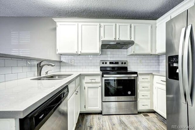 18131 E Arizona Ave Unit F, Aurora, CO 80017 - kitchen with stainless steel appliances, under cabinet range hood, light countertops, a textured ceiling, and white cabinetry