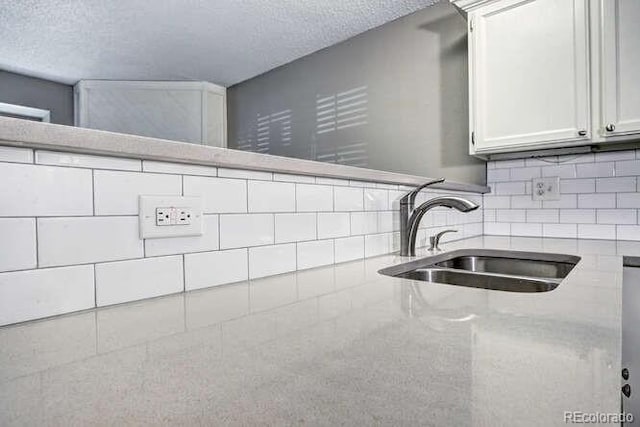 18131 E Arizona Ave Unit F, Aurora, CO 80017 - kitchen view of light stone countertops, a textured ceiling, decorative backsplash, and white cabinets