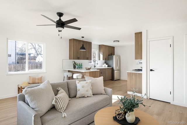 living room with light wood-type flooring, baseboards, and a ceiling fan