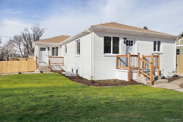 view of front of house with brick siding, fence, and a front lawn