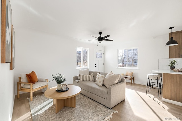 living room featuring light wood finished floors, ceiling fan, and baseboards