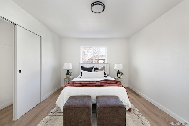 bedroom featuring light wood-type flooring, baseboards, and a closet