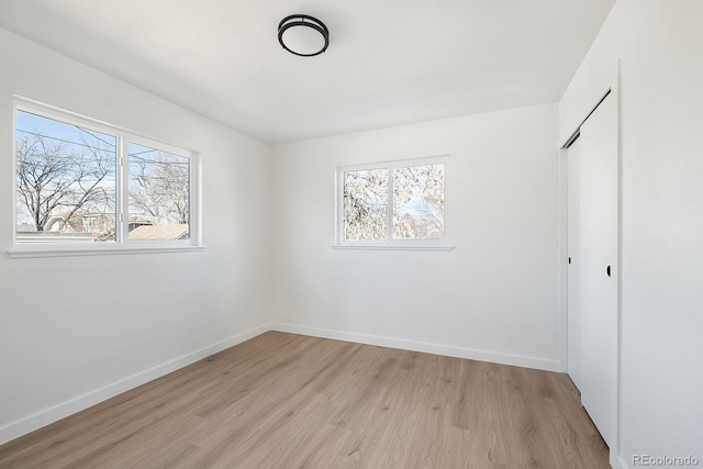 unfurnished bedroom with light wood-type flooring, a closet, and baseboards