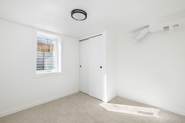 unfurnished bedroom featuring a closet, light colored carpet, and baseboards