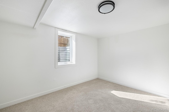 empty room featuring carpet, baseboards, and a textured ceiling