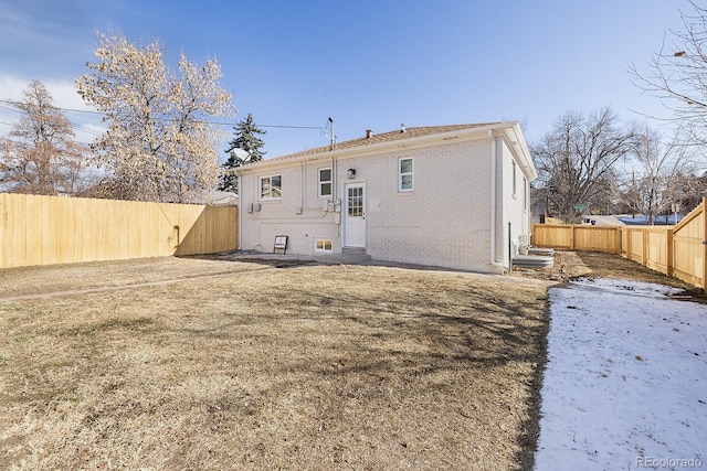 back of property with brick siding and a fenced backyard