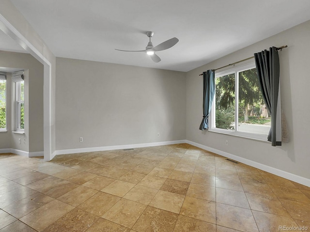 spare room with ceiling fan and baseboards