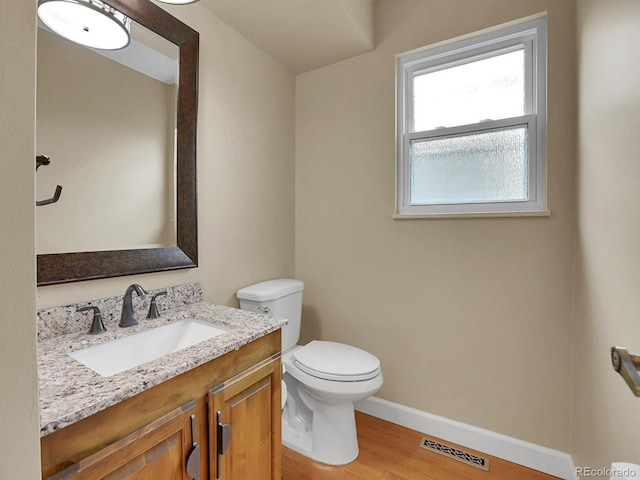 bathroom featuring toilet, wood finished floors, baseboards, and vanity