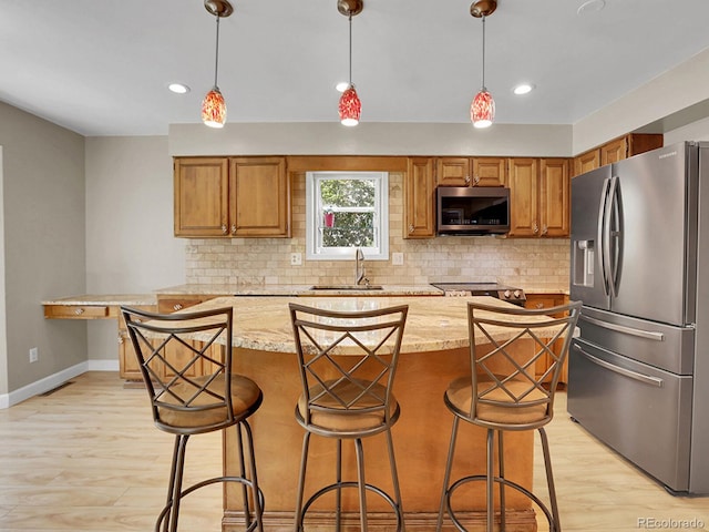 kitchen with appliances with stainless steel finishes, a sink, light wood-type flooring, tasteful backsplash, and recessed lighting