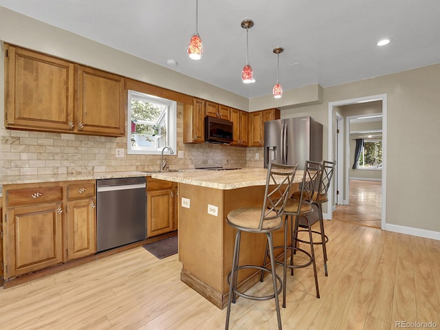 kitchen with stainless steel appliances, brown cabinets, and light wood-style floors