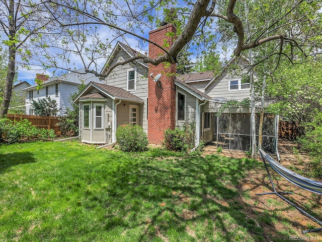 rear view of property with a chimney and a sunroom