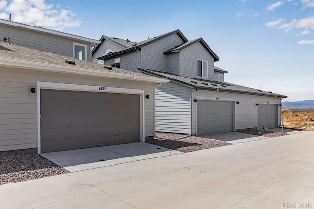 view of front of property featuring a mountain view, a garage, and a shingled roof