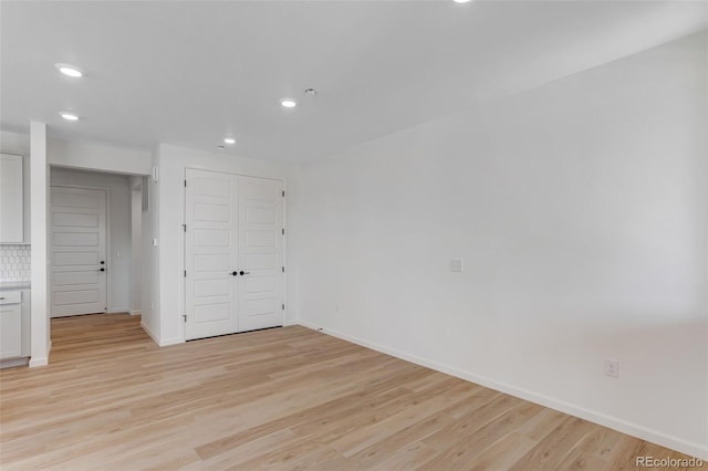 empty room with recessed lighting, light wood-style flooring, and baseboards