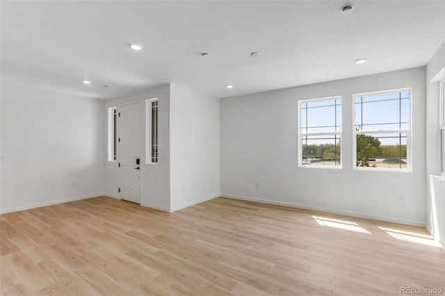 empty room featuring recessed lighting, baseboards, and light wood-type flooring