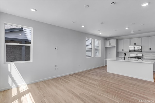 kitchen with appliances with stainless steel finishes, a sink, light wood-style flooring, recessed lighting, and tasteful backsplash