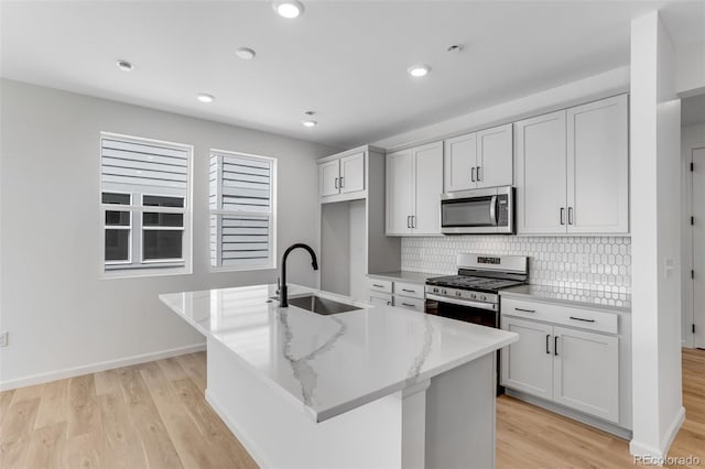 kitchen with stainless steel appliances, a sink, decorative backsplash, light wood-type flooring, and recessed lighting