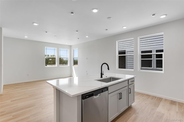 kitchen with stainless steel dishwasher, a sink, light wood-style flooring, a center island with sink, and recessed lighting
