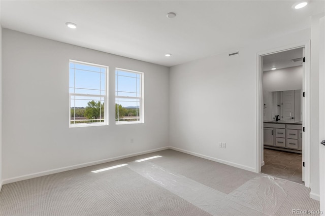 unfurnished bedroom with carpet flooring, baseboards, recessed lighting, a sink, and connected bathroom