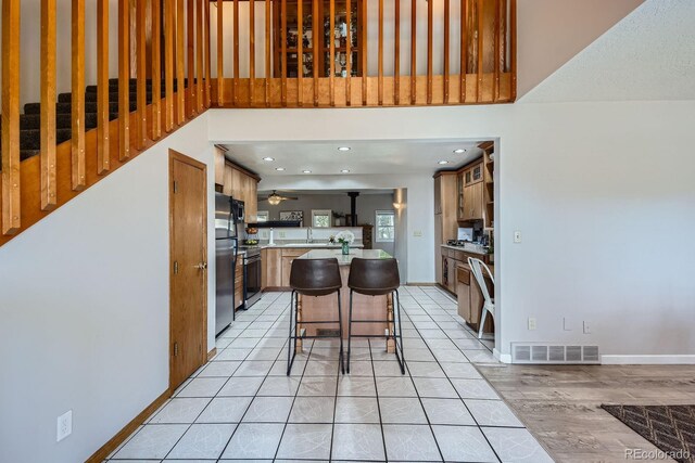 1065 6th St, Berthoud, CO 80513 - kitchen with freestanding refrigerator, light countertops, a towering ceiling, a kitchen bar, and a center island