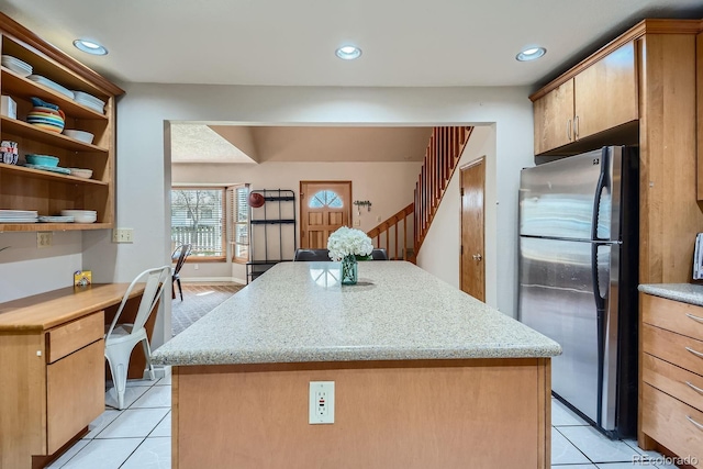 1065 6th St, Berthoud, CO 80513 - kitchen with freestanding refrigerator, light tile patterned floors, a center island, recessed lighting, and light stone counters