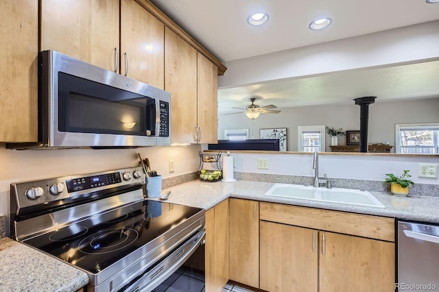 1065 6th St, Berthoud, CO 80513 - kitchen with appliances with stainless steel finishes, light brown cabinets, recessed lighting, ceiling fan, and a wood stove