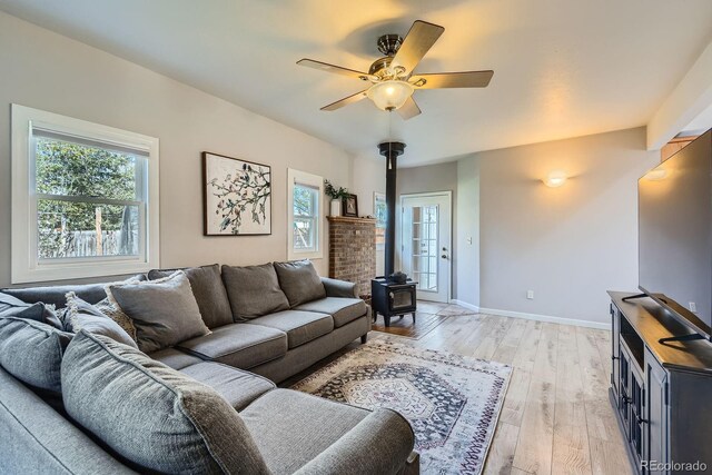 1065 6th St, Berthoud, CO 80513 - living area featuring a wood stove, plenty of natural light, light wood finished floors, and ceiling fan
