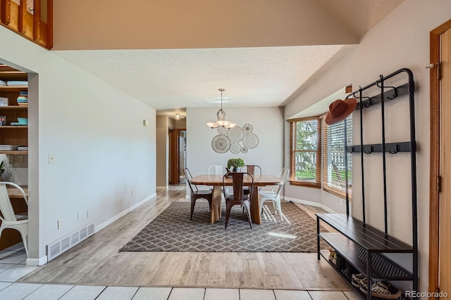 1065 6th St, Berthoud, CO 80513 - dining space featuring wood finished floors, baseboards, a textured ceiling, and a chandelier