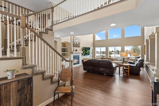 living room featuring hardwood / wood-style flooring, a towering ceiling, and built in features