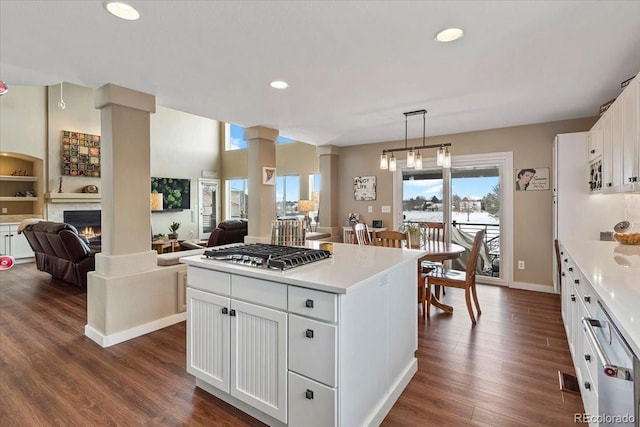 kitchen featuring dark hardwood / wood-style floors, decorative light fixtures, stainless steel gas stovetop, white cabinetry, and a center island