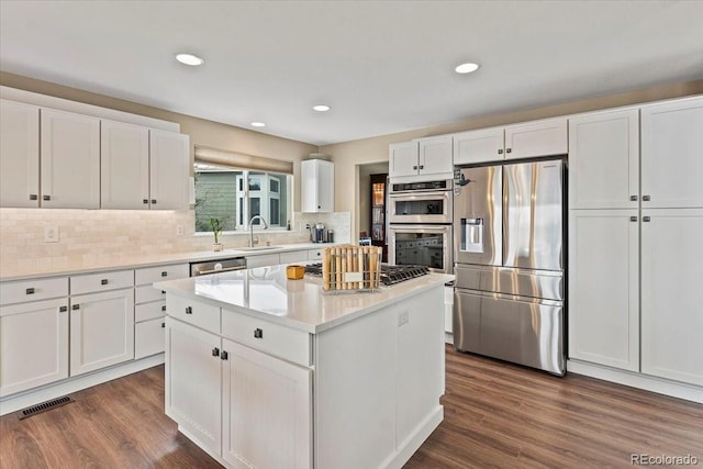 kitchen with stainless steel appliances, a center island, white cabinets, and dark hardwood / wood-style flooring