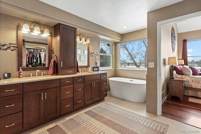 bathroom with vanity, a tub to relax in, tile patterned floors, and a textured ceiling