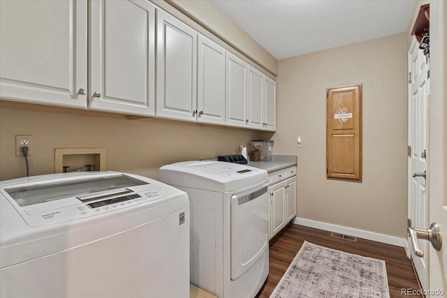 laundry area featuring dark hardwood / wood-style floors, washing machine and dryer, and cabinets