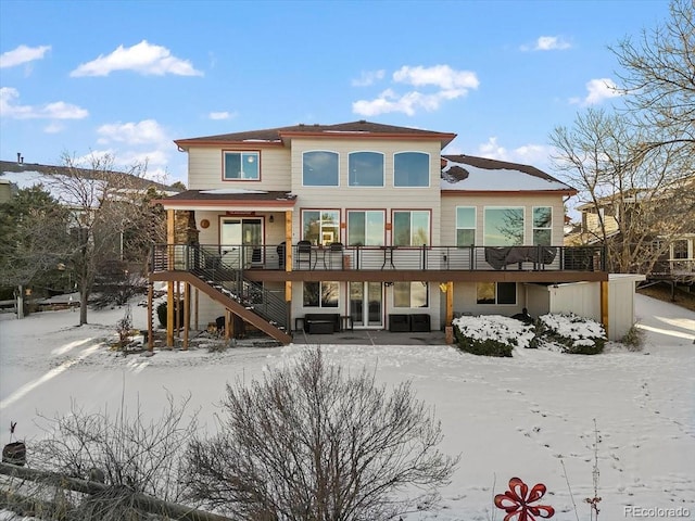 snow covered rear of property with a deck