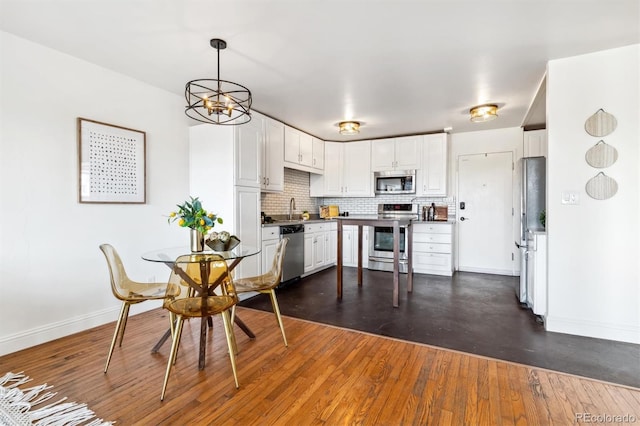 kitchen with white cabinets, appliances with stainless steel finishes, dark wood-type flooring, pendant lighting, and sink