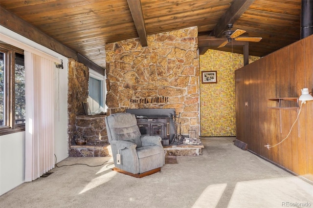 unfurnished room featuring a wood stove, lofted ceiling with beams, light carpet, and wooden ceiling