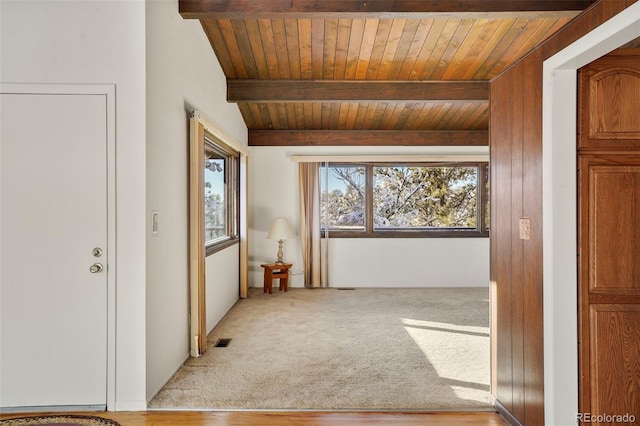 interior space featuring light colored carpet, wooden ceiling, and beam ceiling