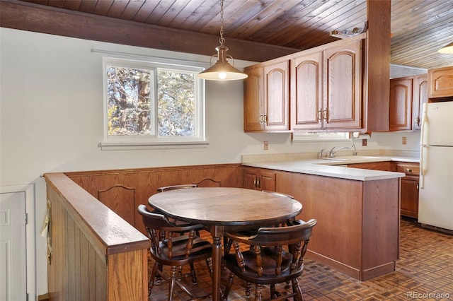 kitchen with sink, kitchen peninsula, wood ceiling, white fridge, and pendant lighting