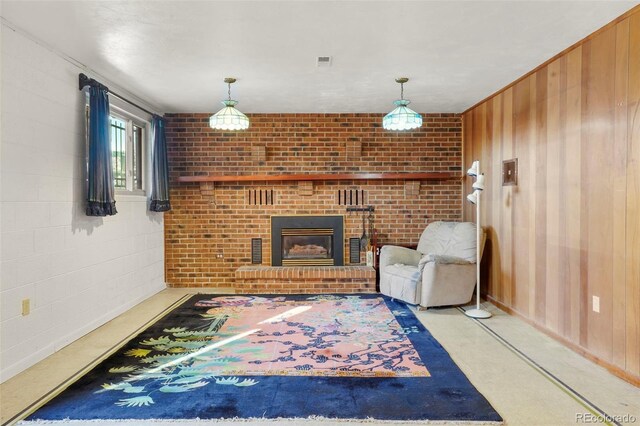 living room with a fireplace, brick wall, wooden walls, and light carpet