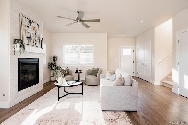 living room featuring ceiling fan, wood-type flooring, and a fireplace