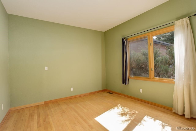 unfurnished room with visible vents, baseboards, and wood finished floors