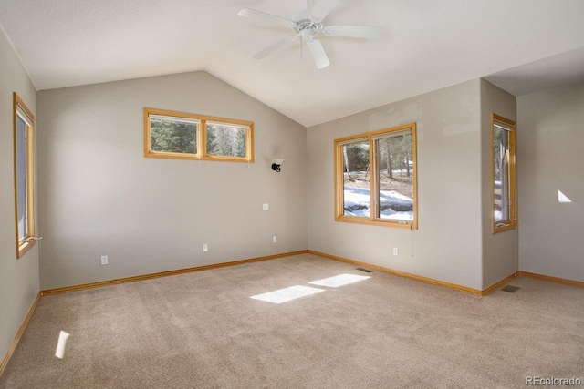 carpeted empty room with lofted ceiling, a ceiling fan, baseboards, and visible vents