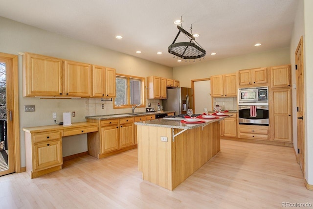 kitchen featuring a sink, stainless steel appliances, backsplash, and light brown cabinets