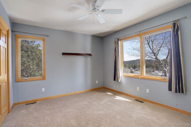 unfurnished room featuring visible vents, baseboards, carpet, and ceiling fan