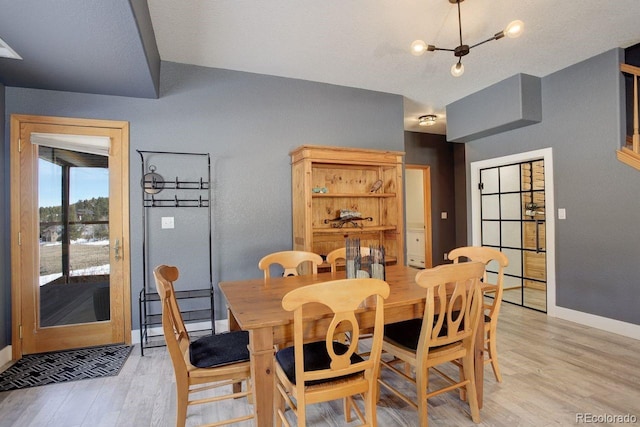 dining room featuring a notable chandelier, light wood-type flooring, and baseboards